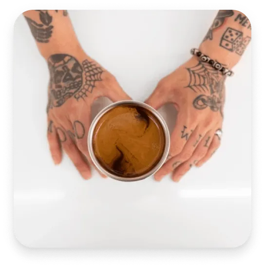tattooed hands holding a cup of coffee